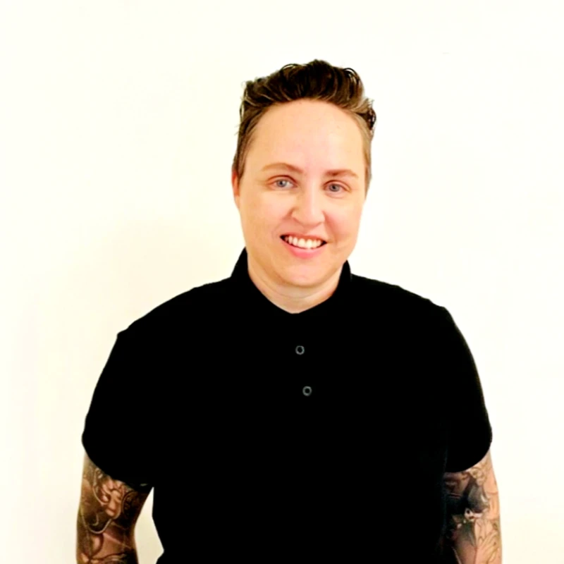Diana Thomson, smiling, in a black shirt against a plain white wall.